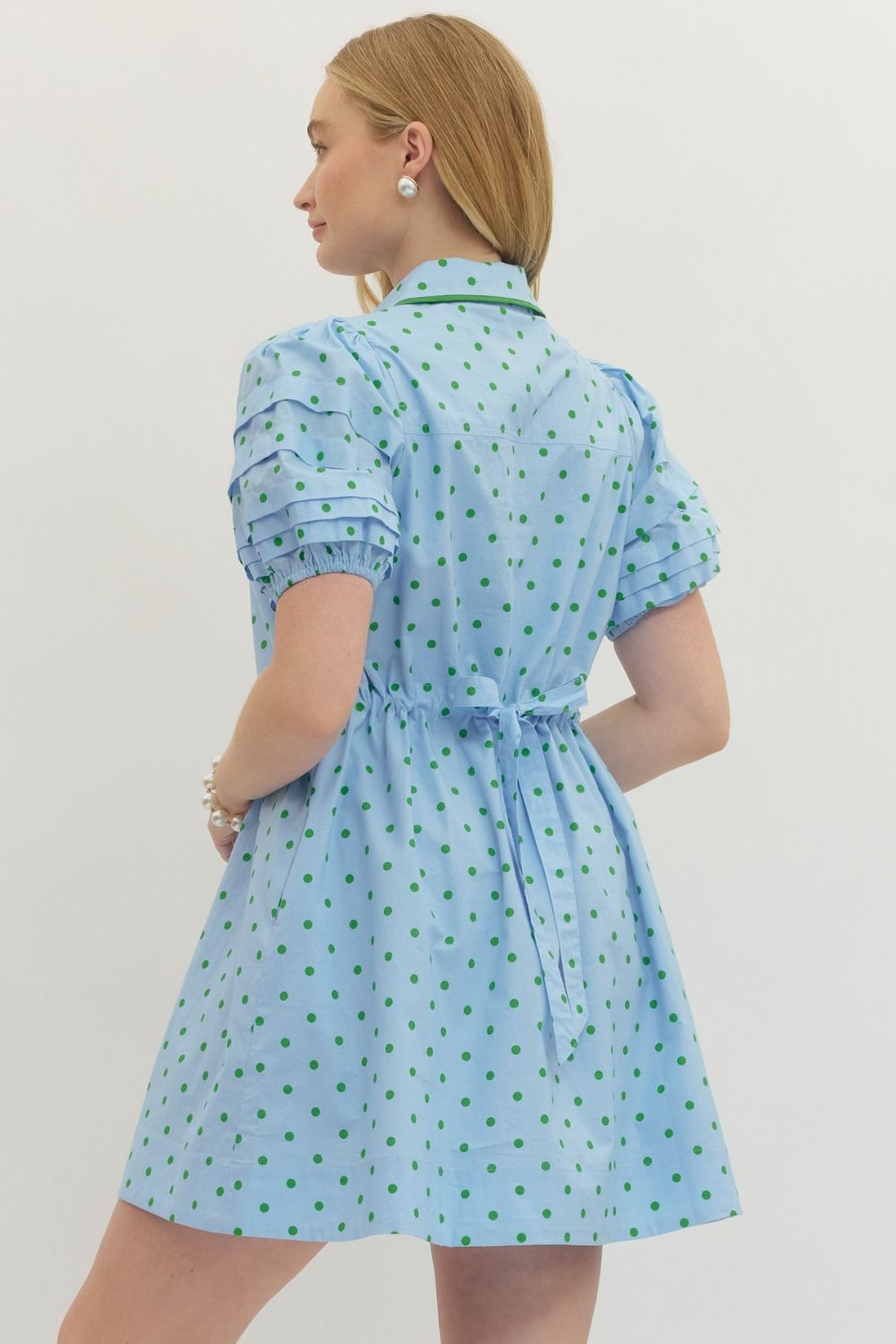 Woman wearing a light blue dress with a subtle pattern on a plain background
