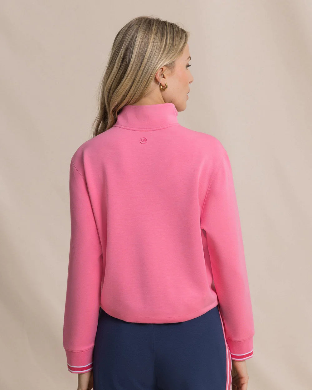 Woman wearing a pink quarter-zip sweatshirt on a beige background