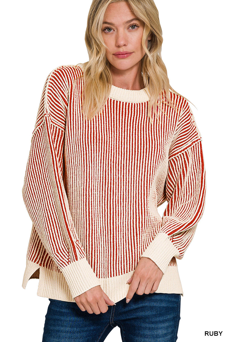 A woman wearing a cream and rust red vertically striped knit sweater with balloon sleeves and a crew neck, paired with blue jeans against a white background.