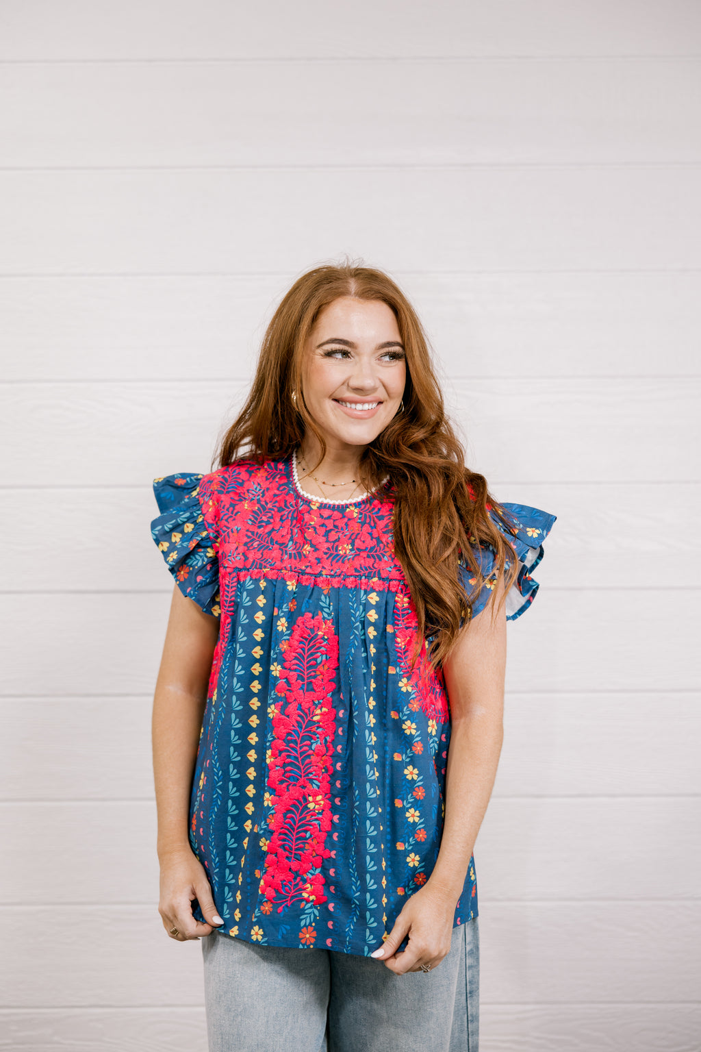 Woman wearing a colorful patterned top against a plain background