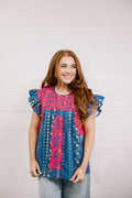 Woman wearing a colorful patterned top against a plain background