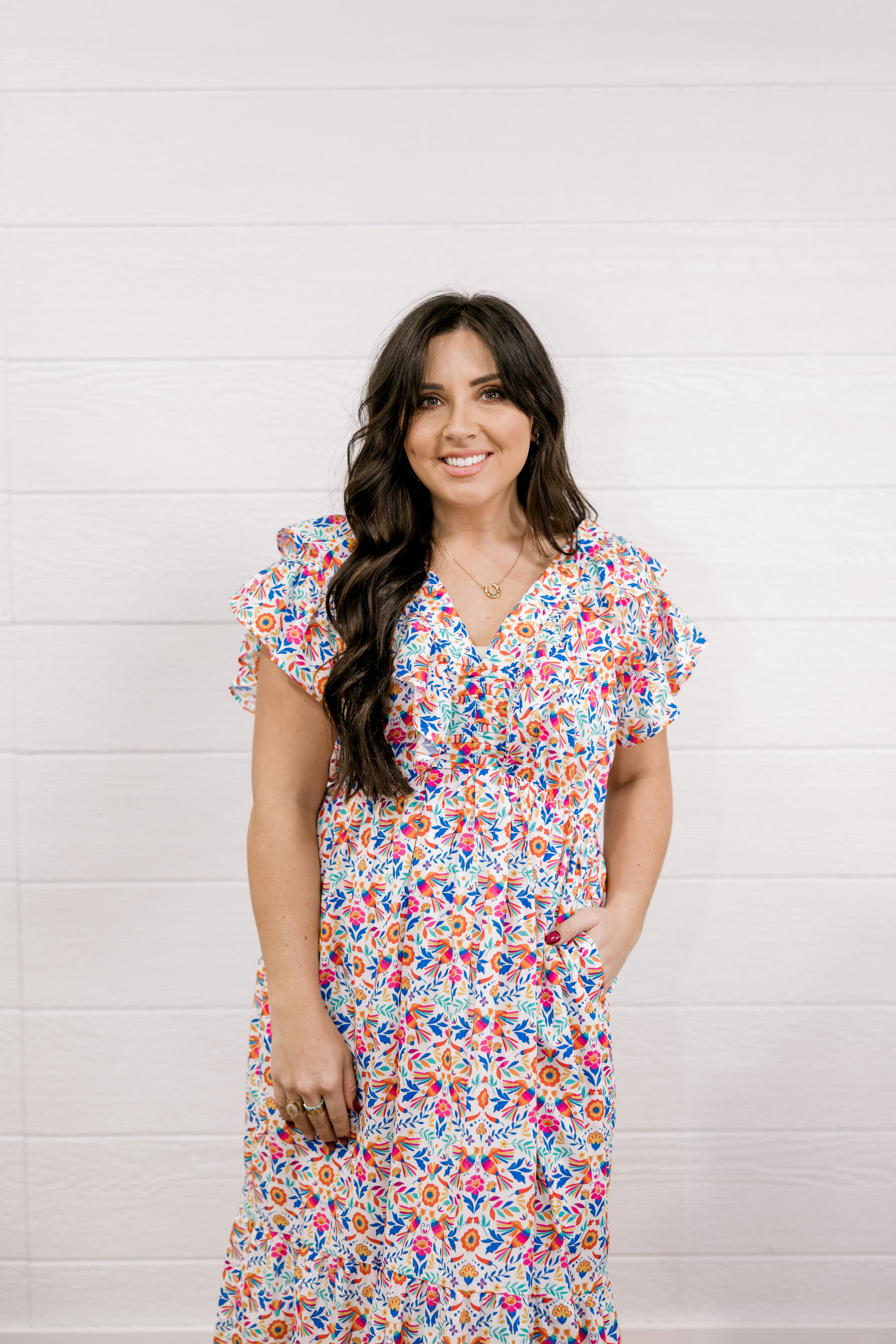 Woman wearing a colorful floral dress against a white background