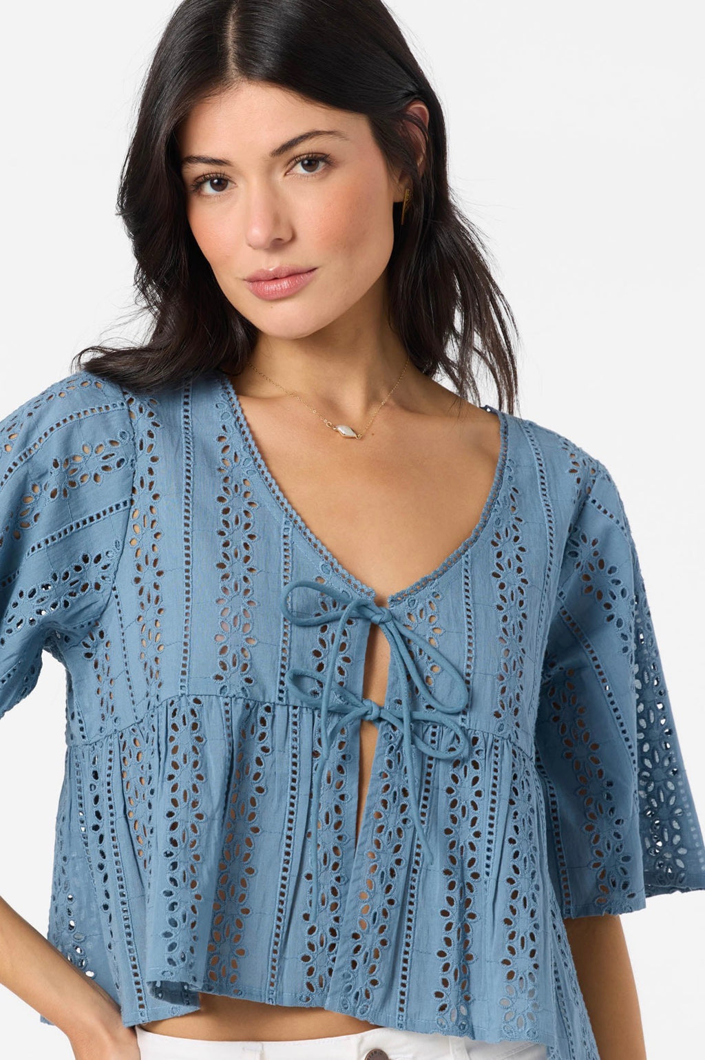 Woman wearing a blue lace top against a white background