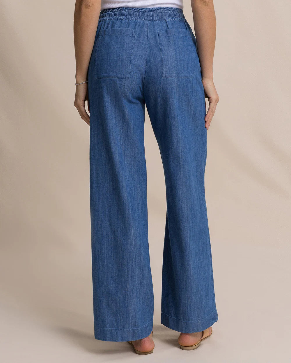 Blue denim pants worn by a person on a beige background
