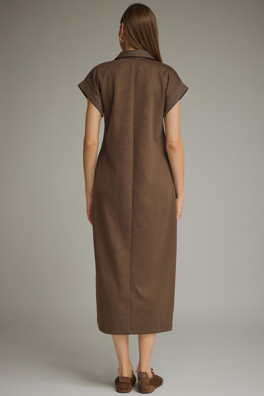 Woman wearing a brown dress against a plain background