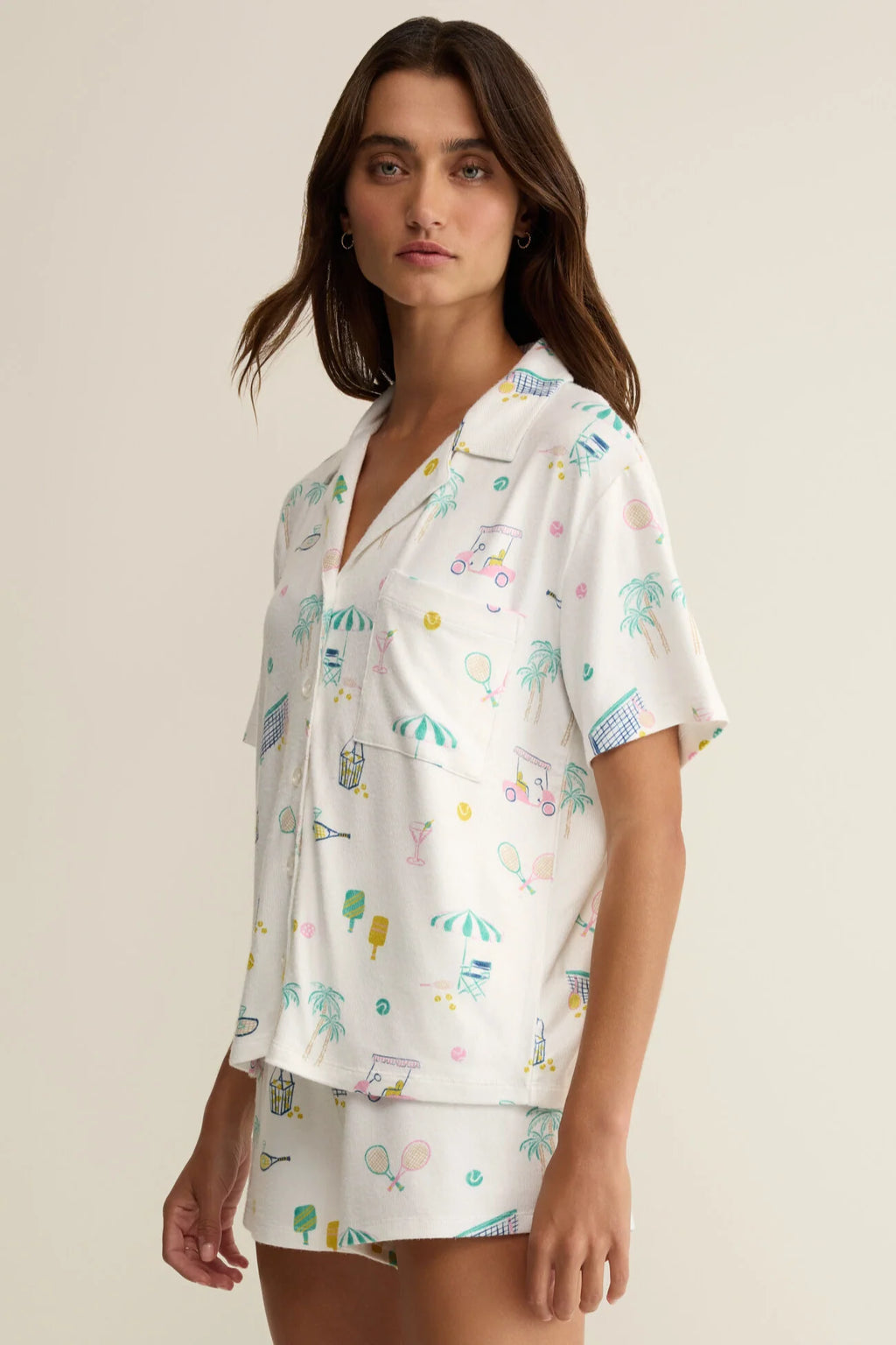 Woman wearing a white pajama set with colorful patterns on a beige background