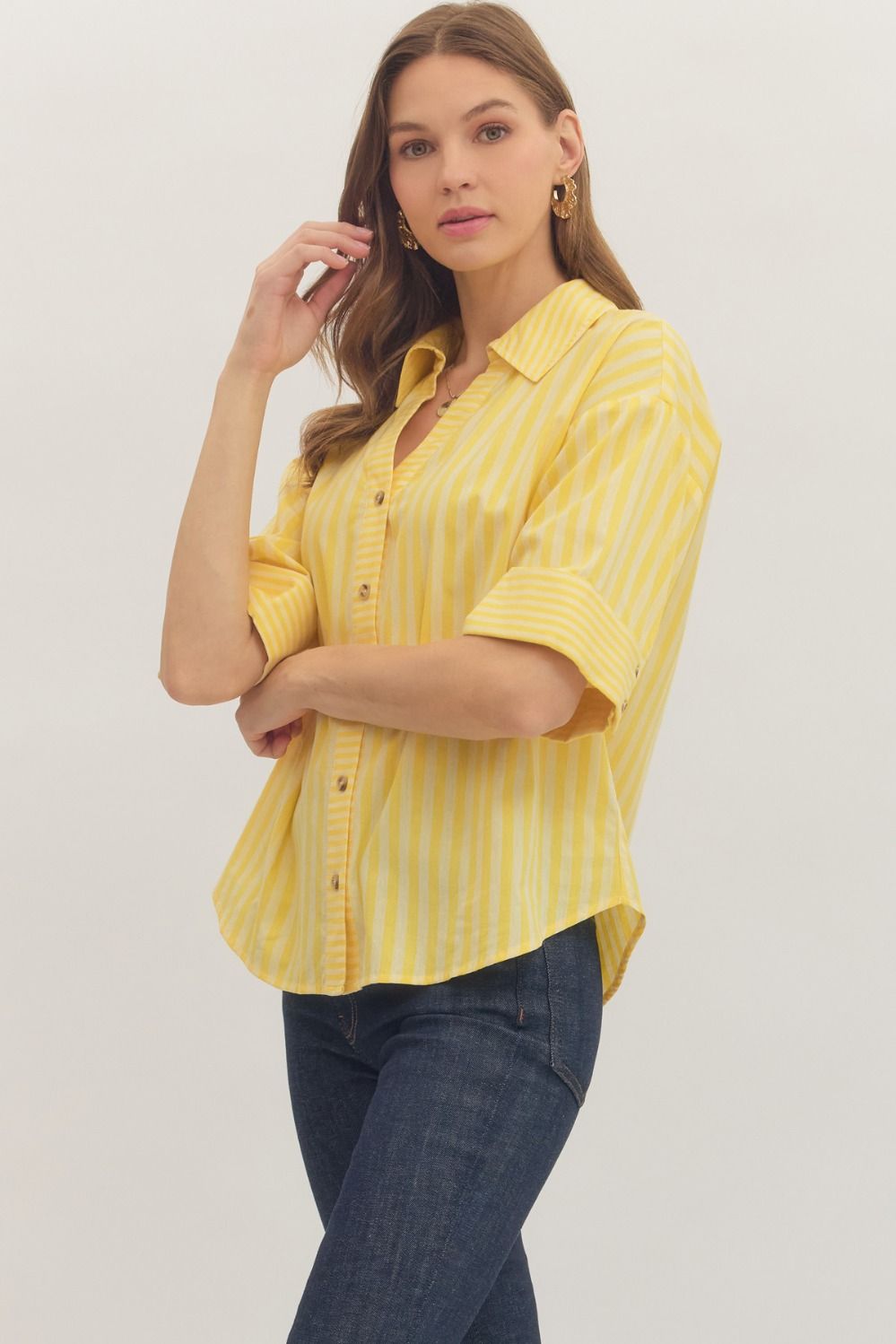 Woman wearing a yellow striped shirt and blue jeans on a white background