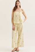 Woman wearing a yellow polka dot top and pants on a white background