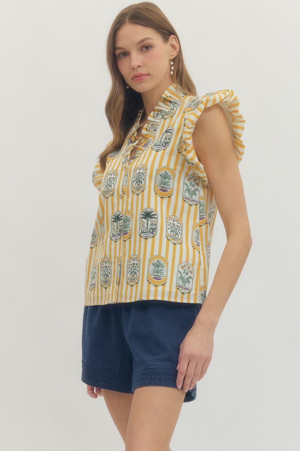 Woman wearing a yellow patterned sleeveless top and blue shorts on a white background