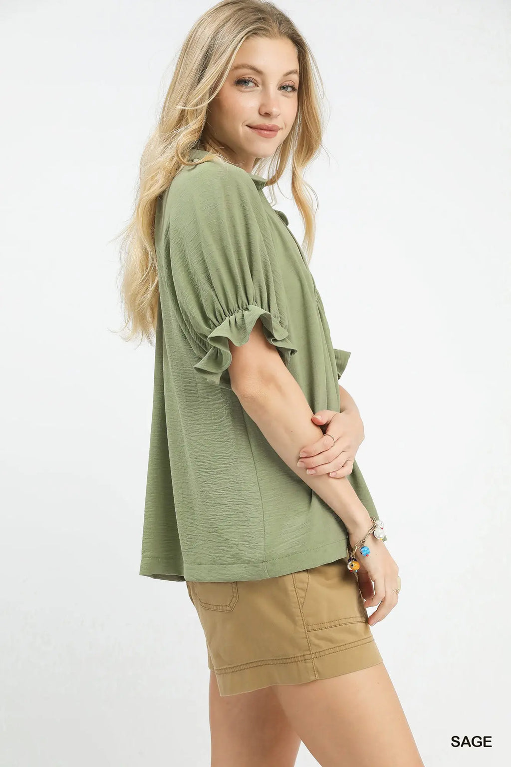 Woman wearing a green top and beige shorts on a white background