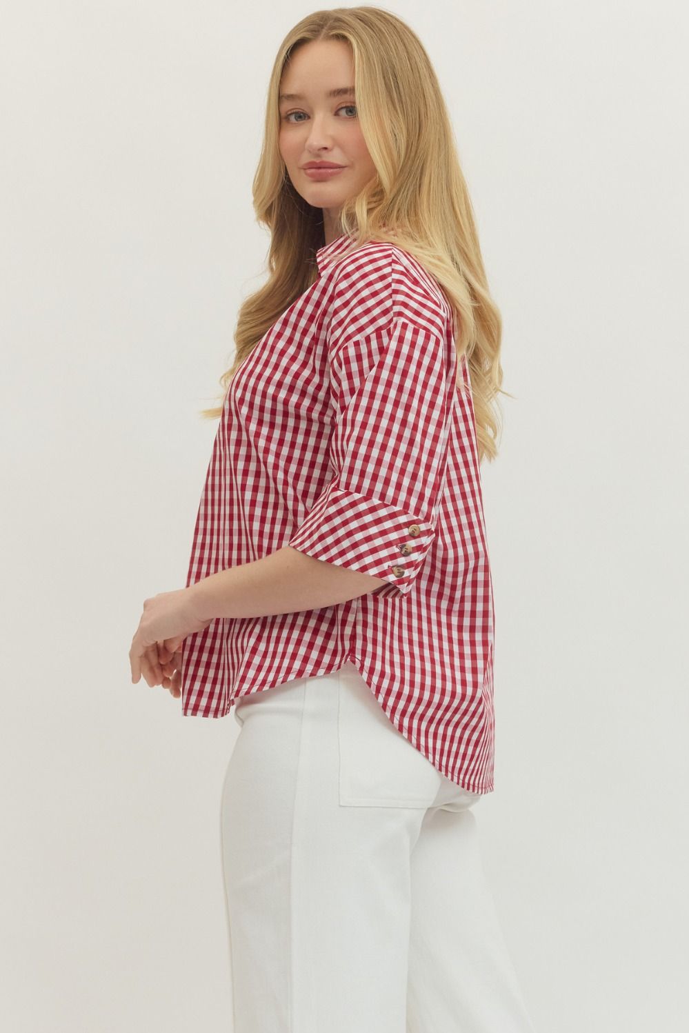 Woman wearing a red and white checkered shirt against a plain background