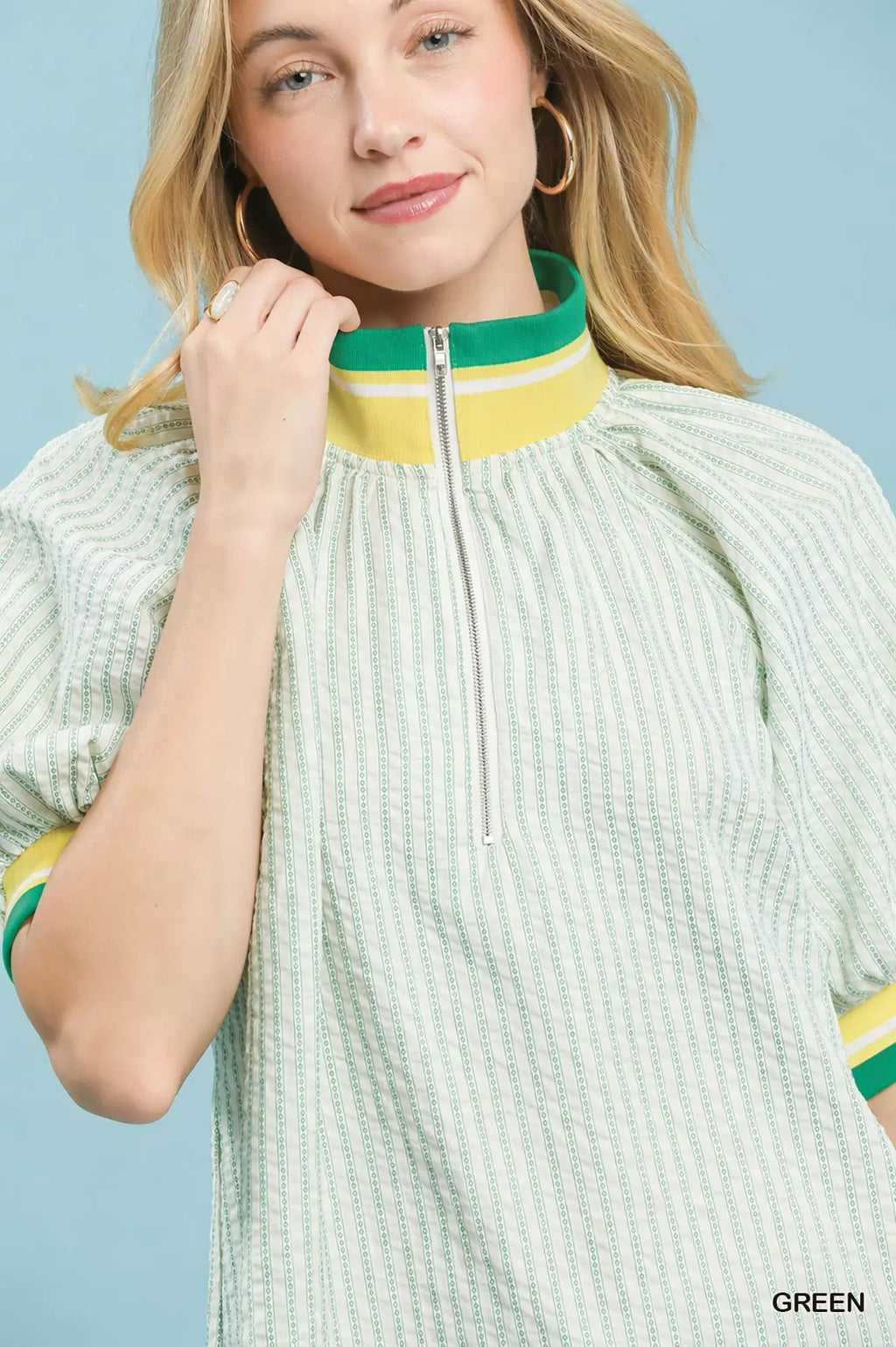 Woman wearing a light green dress with yellow accents on a blue background