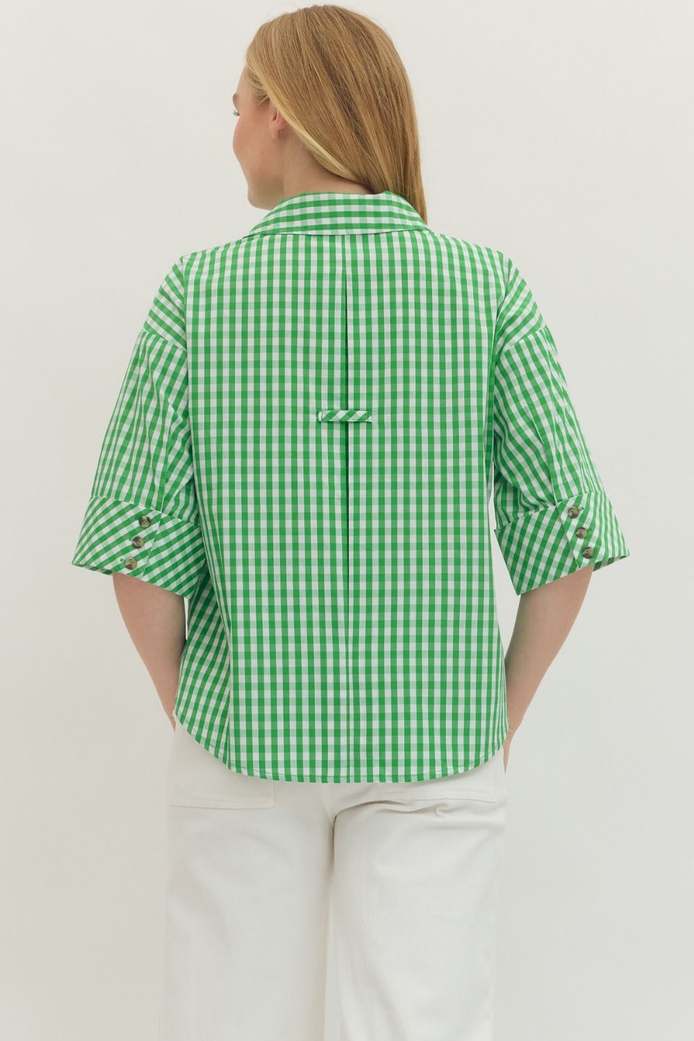 Person wearing a green and white checkered shirt on a plain background