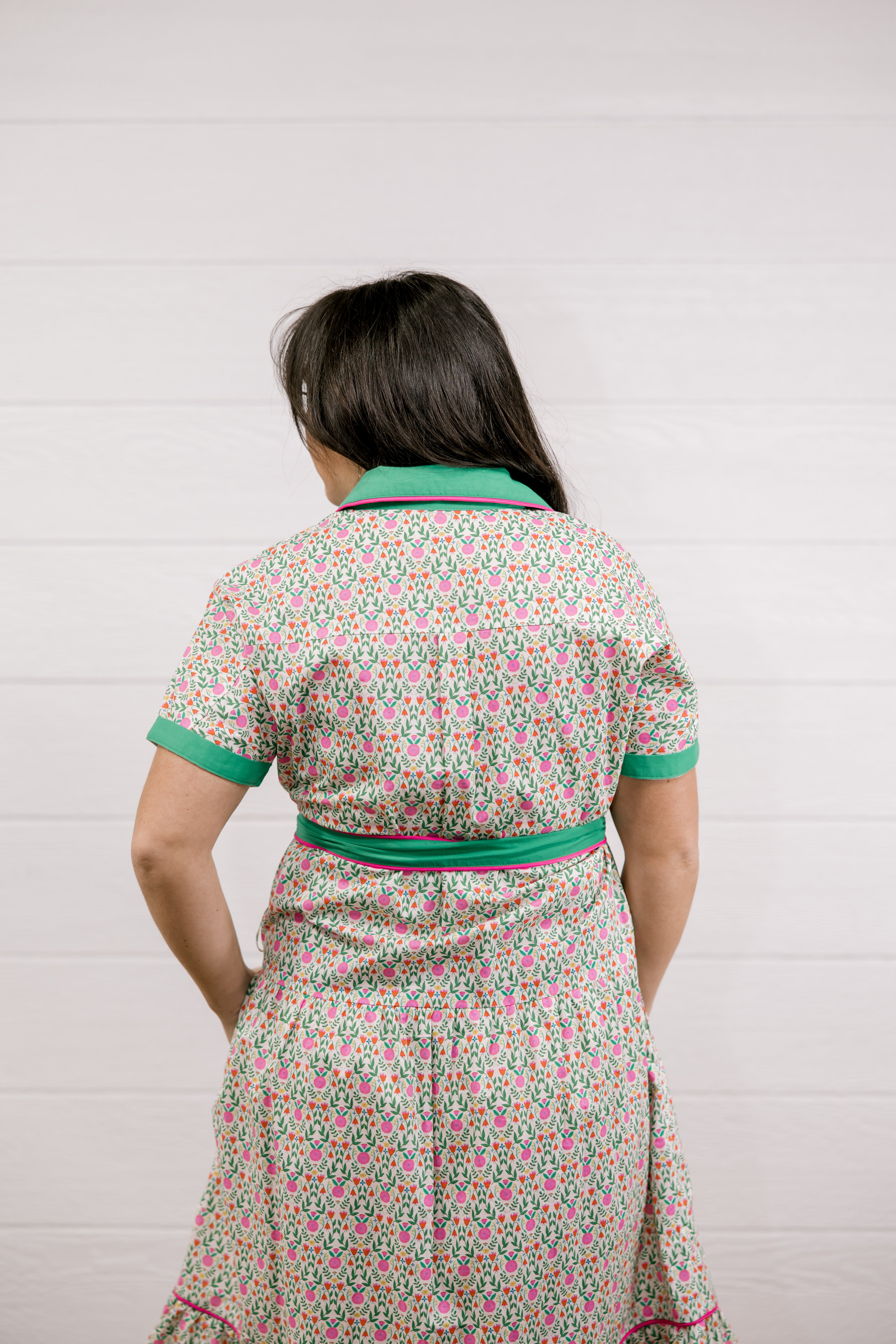 Woman wearing a floral dress with green trim against a white background