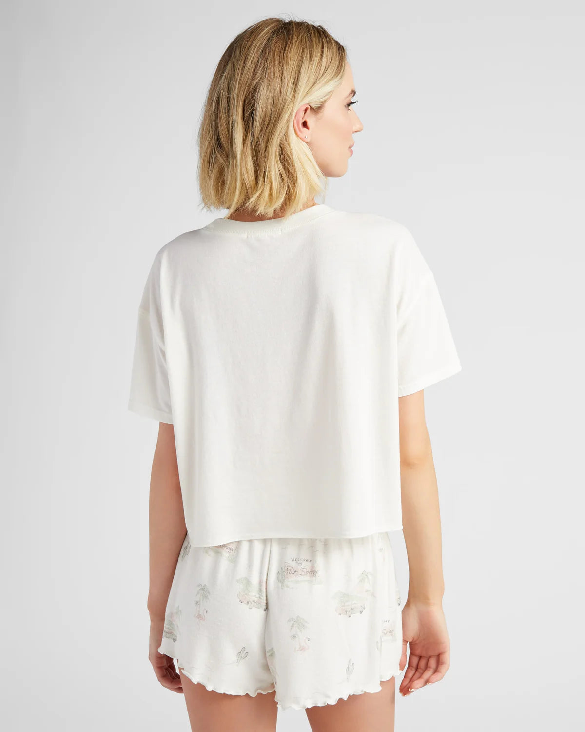 Woman wearing a white outfit with lace details on a plain background