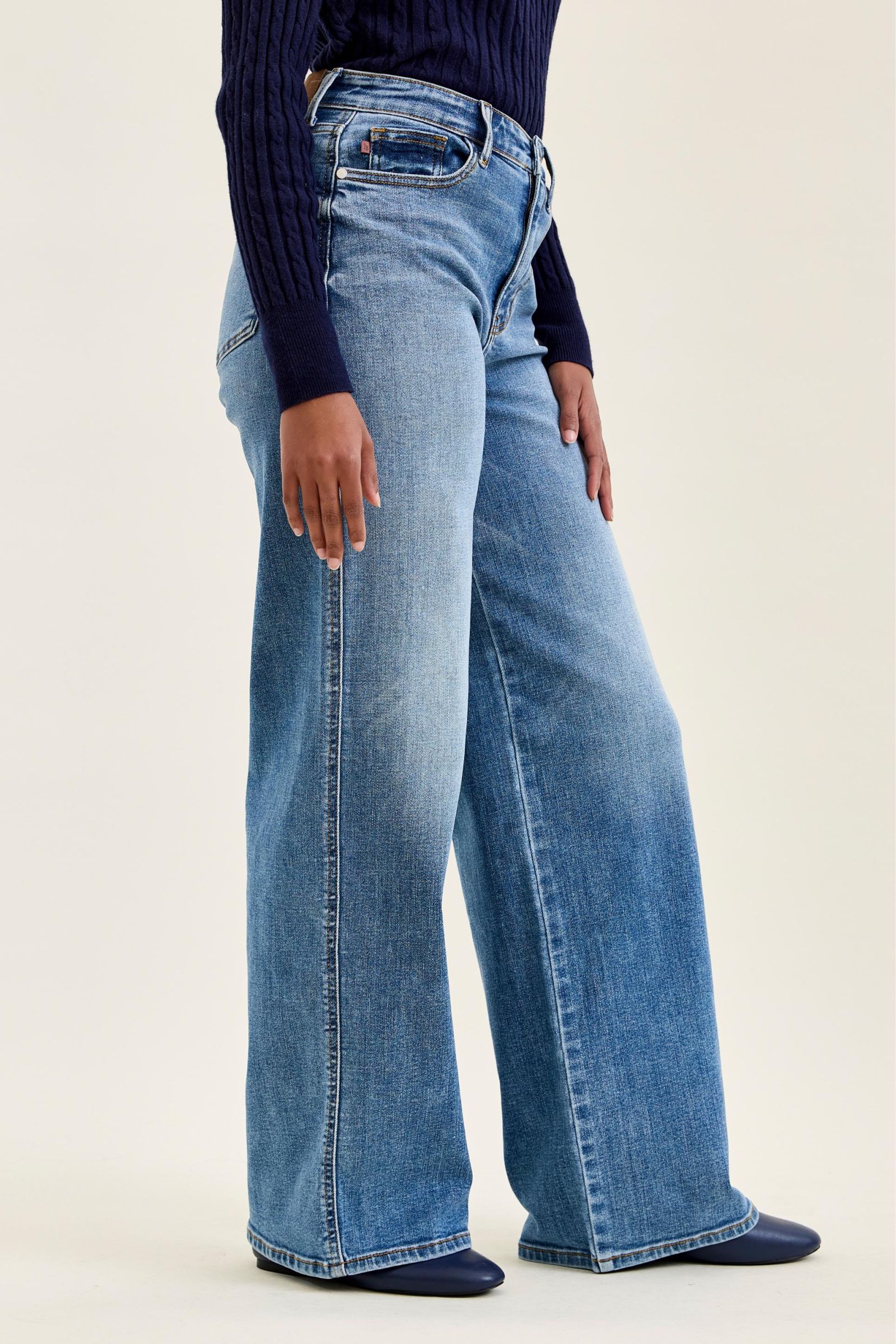 Person wearing blue jeans and a dark top on a white background