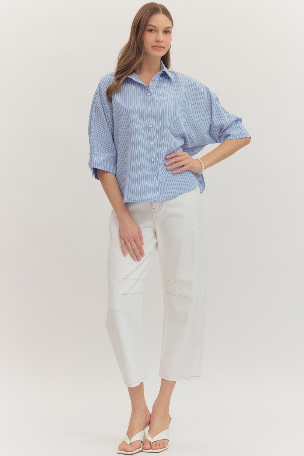 Woman wearing a blue checkered shirt and white pants on a white background