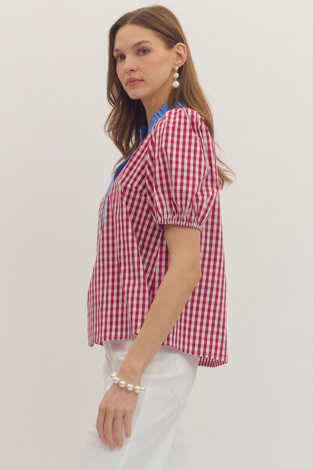 Woman wearing a red and white checkered blouse on a plain background