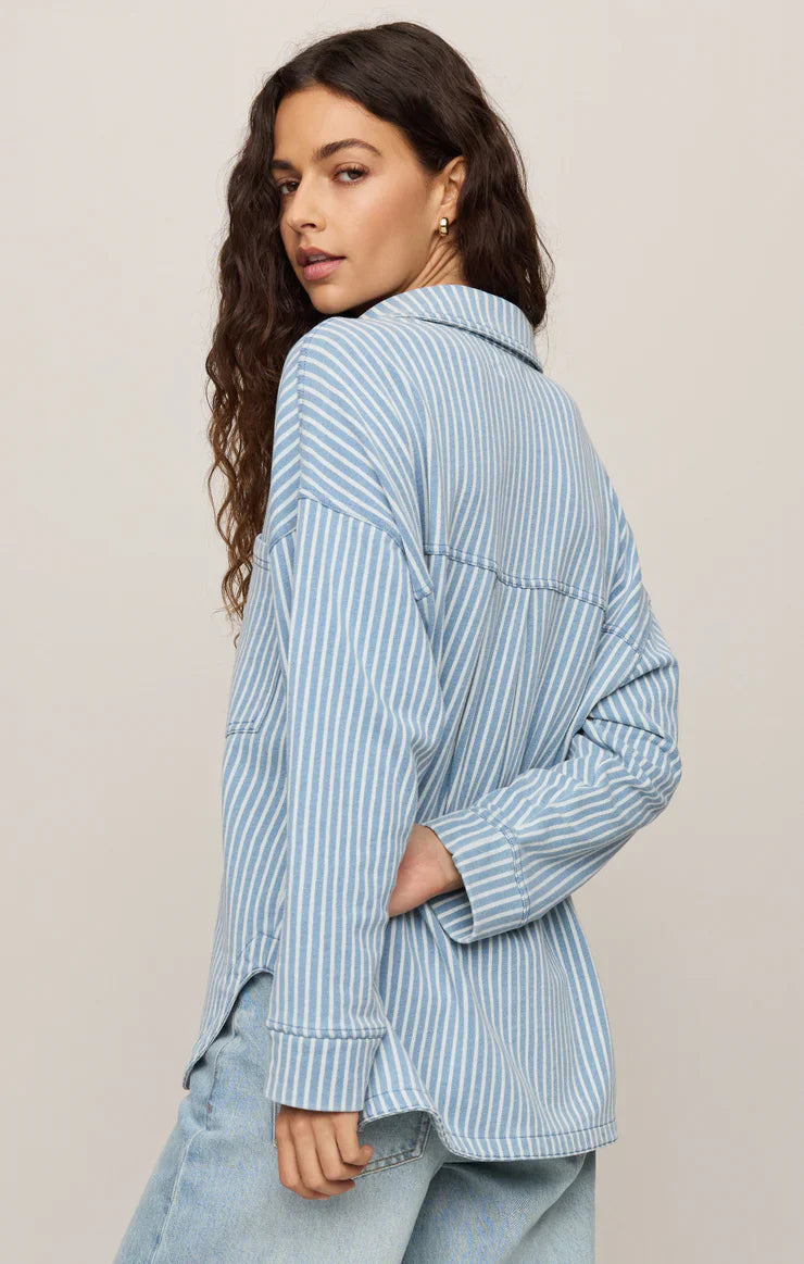 Woman wearing a light blue striped shirt against a beige background