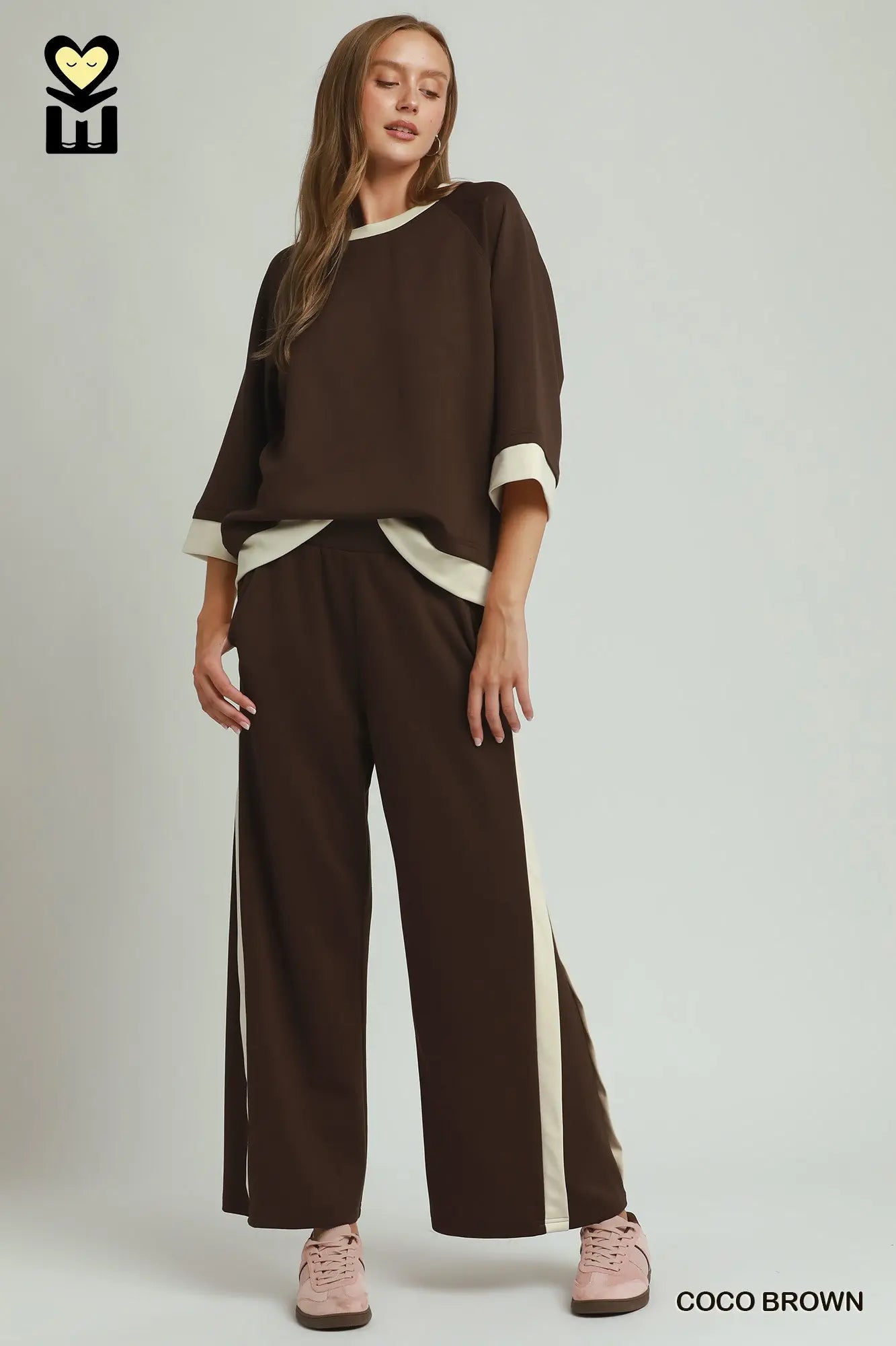 Woman wearing a brown outfit with white accents on a plain background