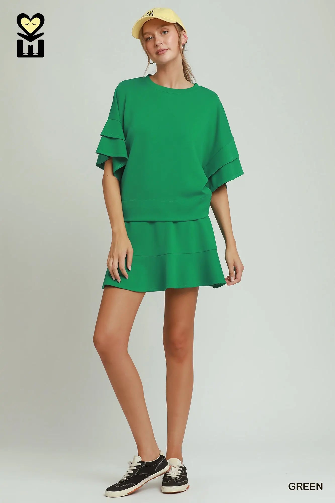 Woman wearing a green dress with ruffled sleeves on a white background