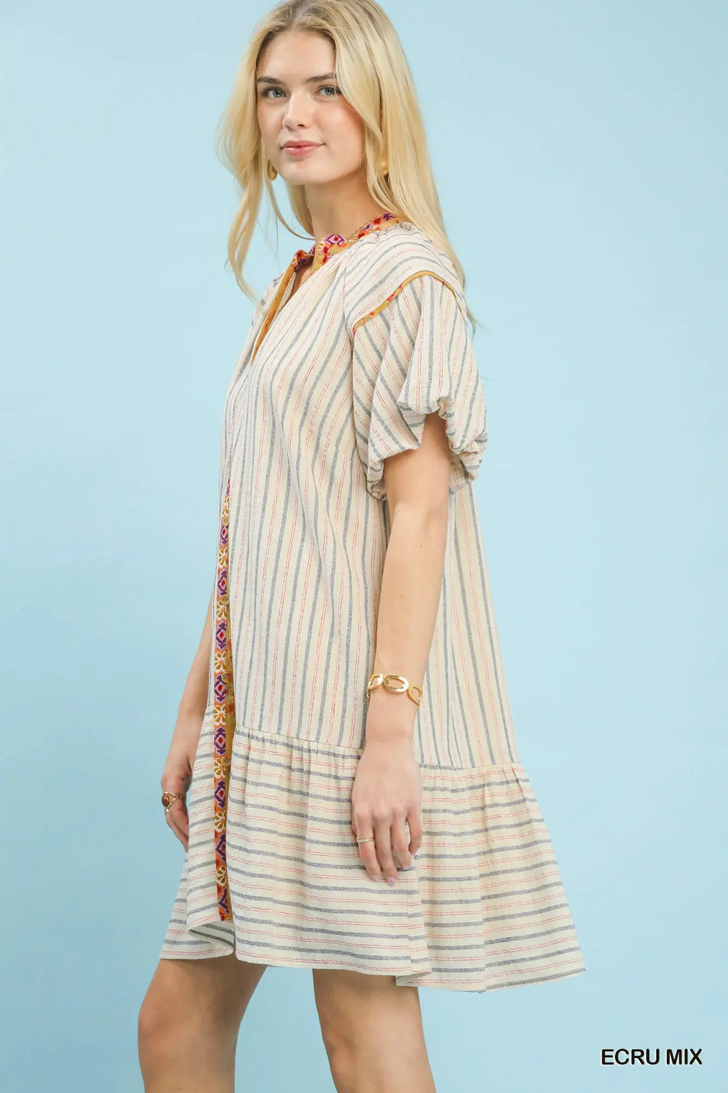 Woman wearing a striped dress with a scarf against a light blue background