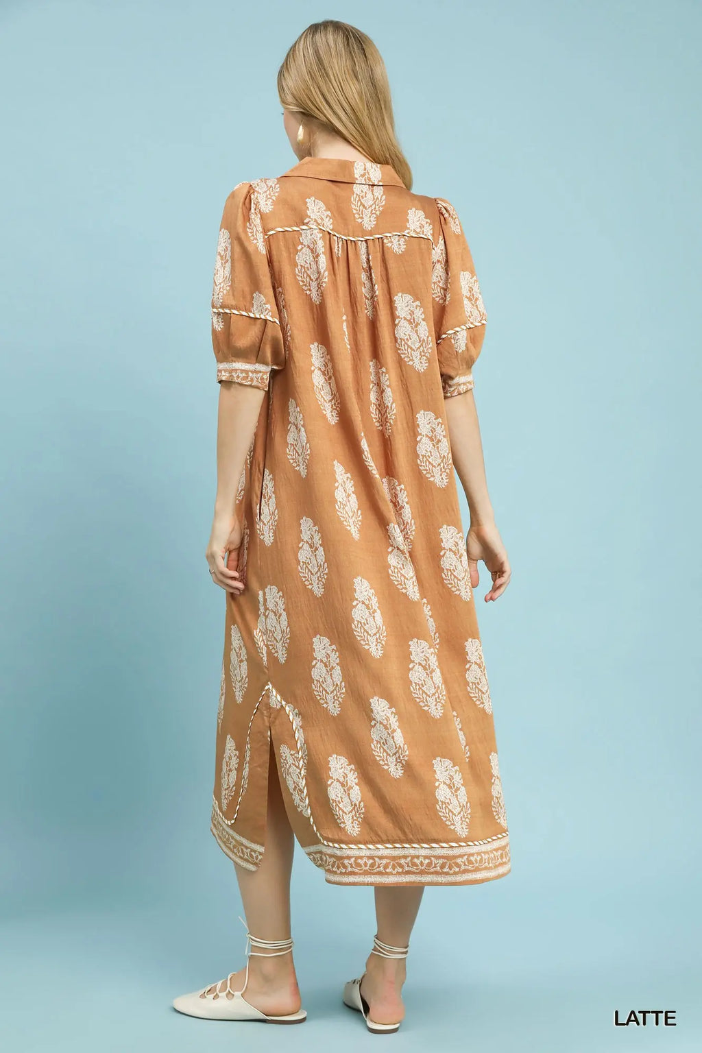 Woman wearing a brown dress with white floral pattern on a light blue background