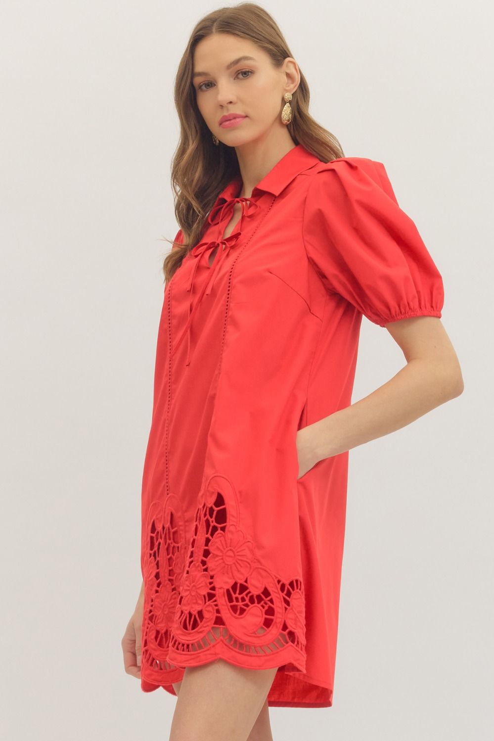 Woman wearing a red dress with lace details on a plain background