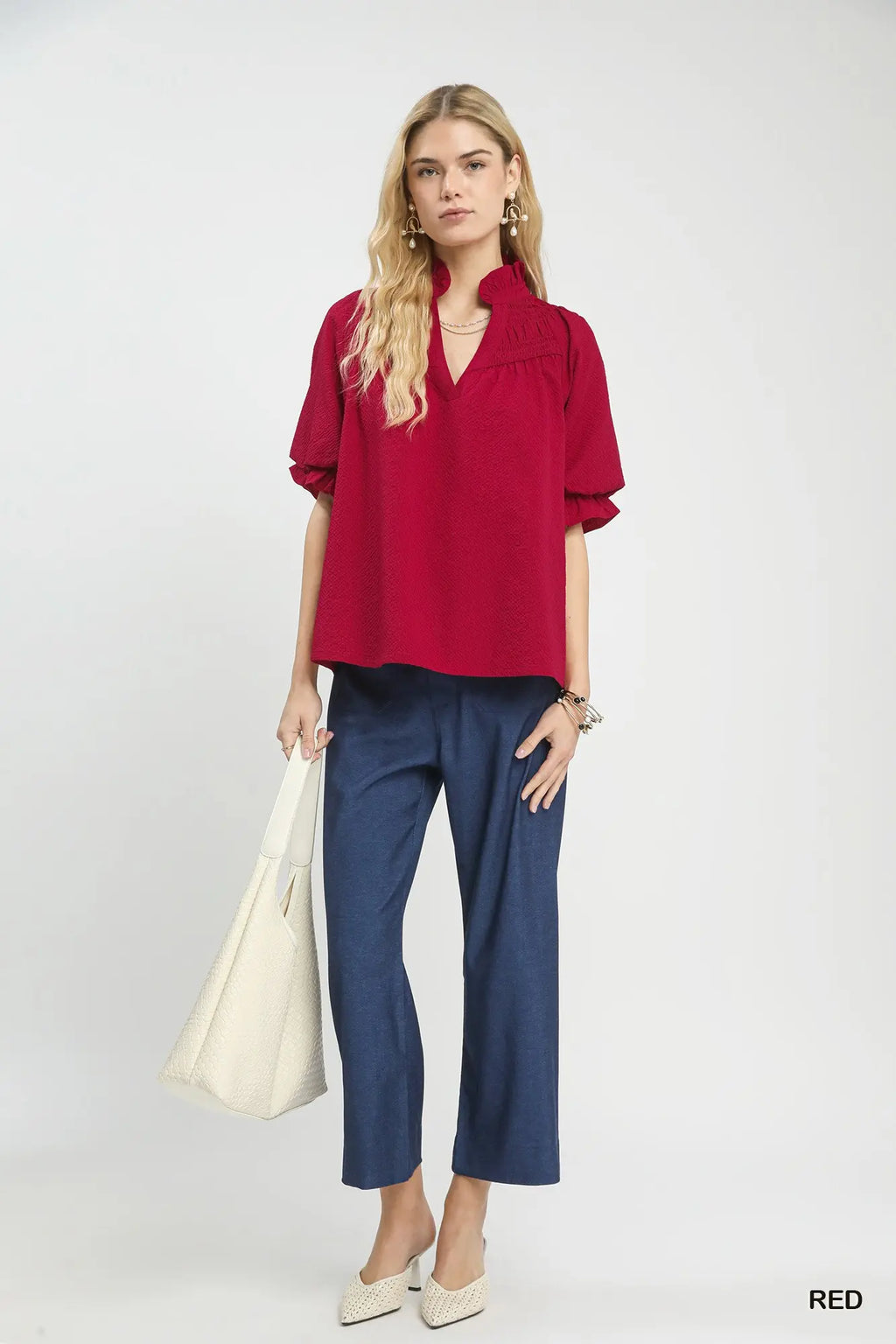 Woman wearing a red blouse and blue pants with a white background
