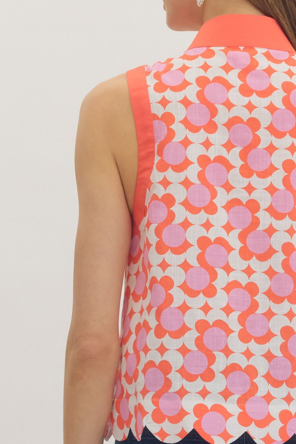 Close-up of a sleeveless top with a geometric pattern in pink and orange on a plain background