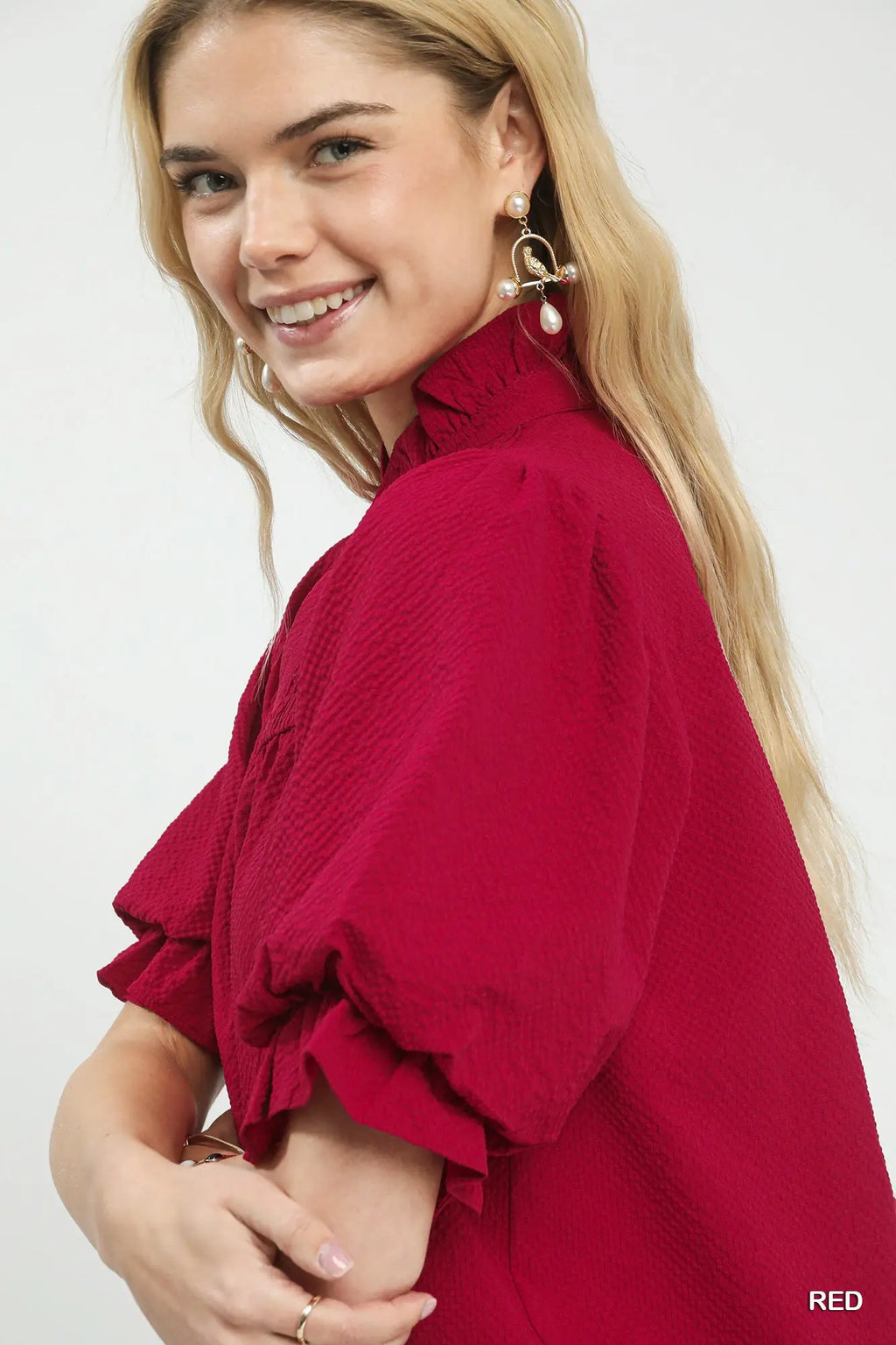 Woman wearing a red blouse with ruffled sleeves on a white background