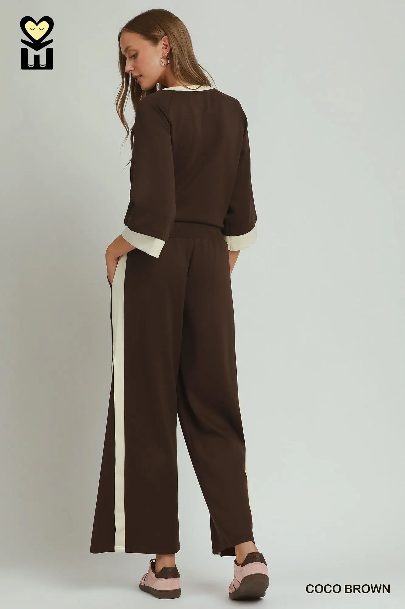 Woman wearing a brown jumpsuit with a white stripe on a plain background