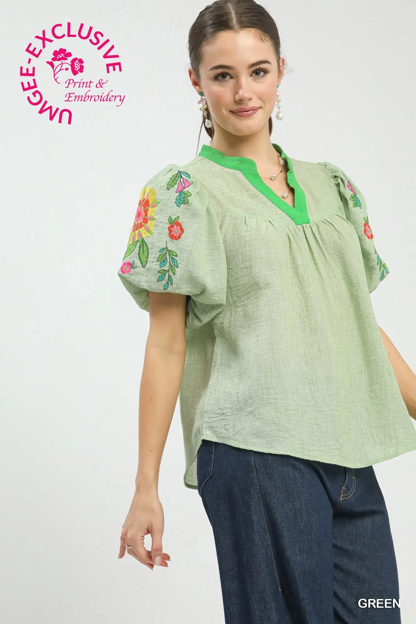 Woman wearing a green embroidered blouse with floral designs on a white background