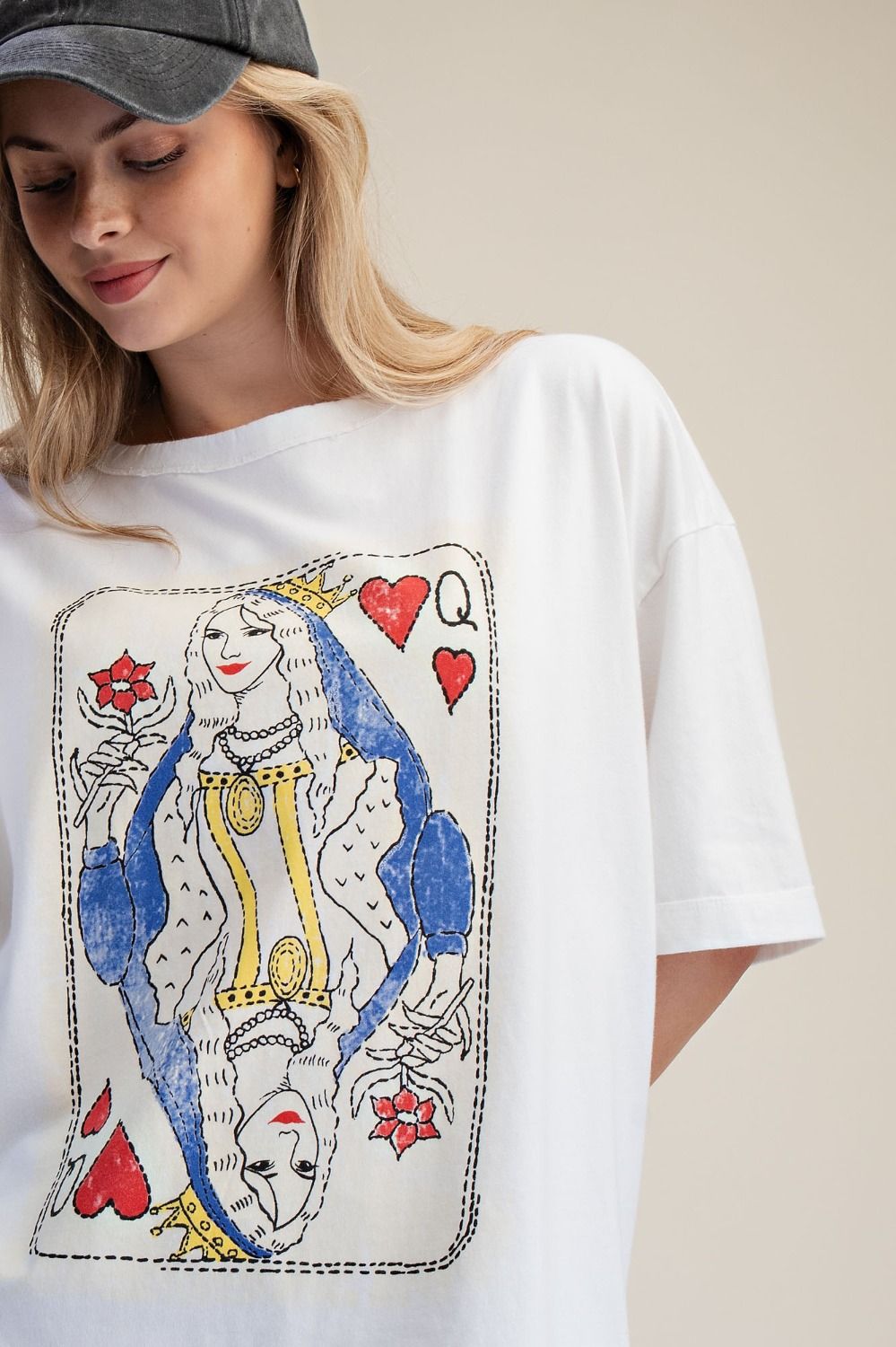 Woman wearing a white t-shirt with a colorful graphic design of a queen from a card game.