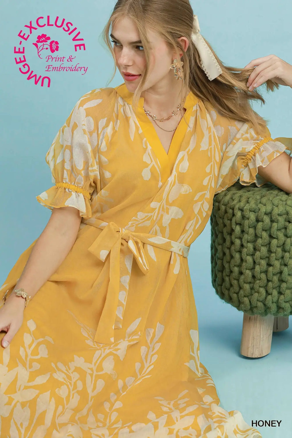 Woman wearing a yellow floral dress against a blue background with 'UMEE Exclusive' branding.