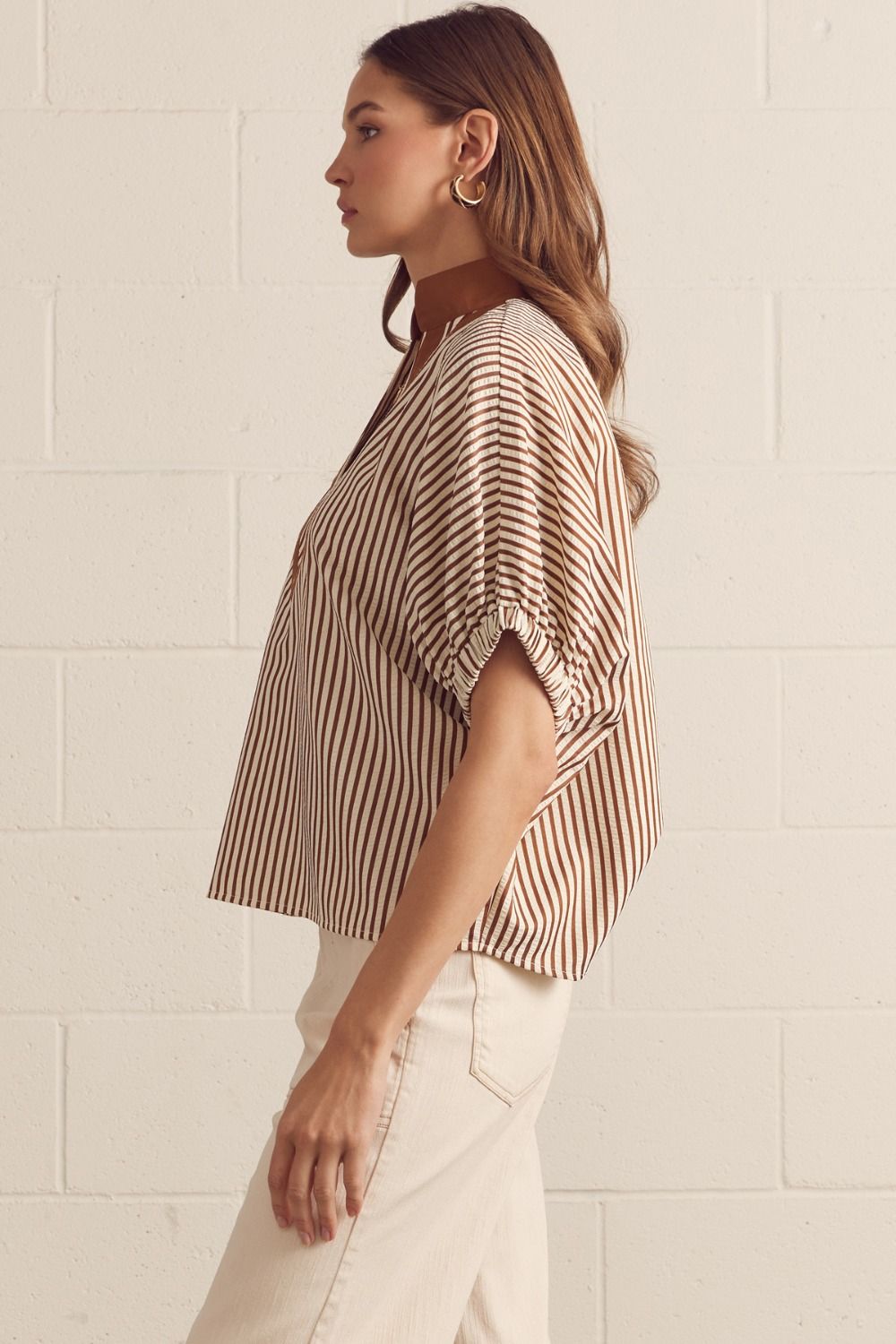Woman wearing a striped blouse against a light tiled wall