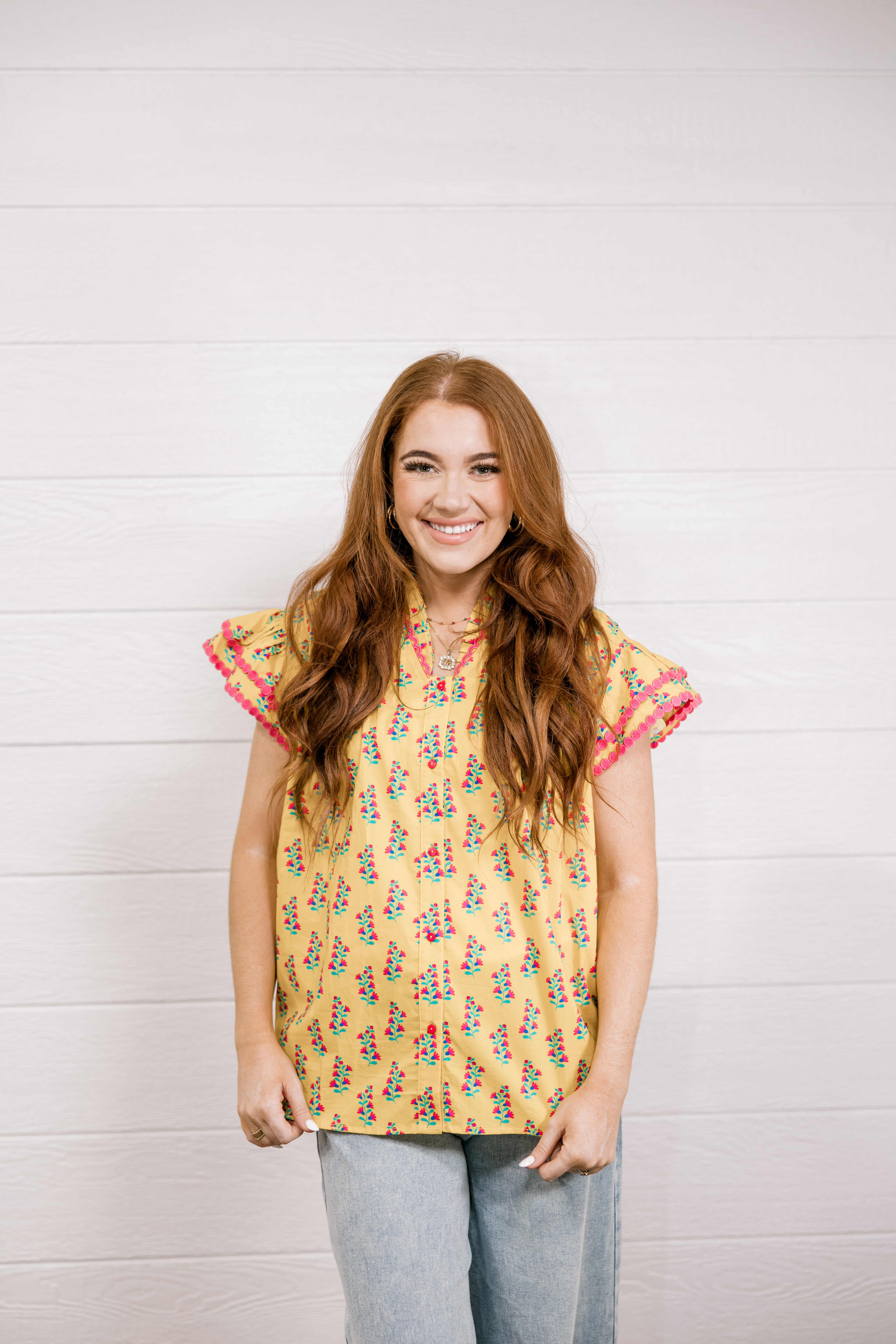 Woman wearing a yellow floral blouse against a white background