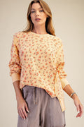 Woman wearing a floral blouse and gray pants against a beige background
