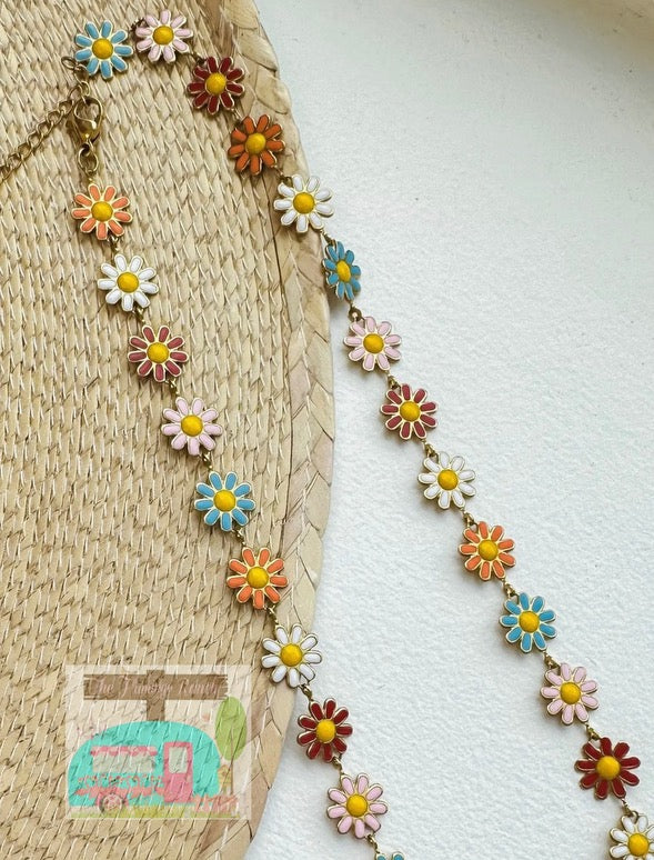 Colorful flower-shaped necklace on a textured surface with a small embroidered design.