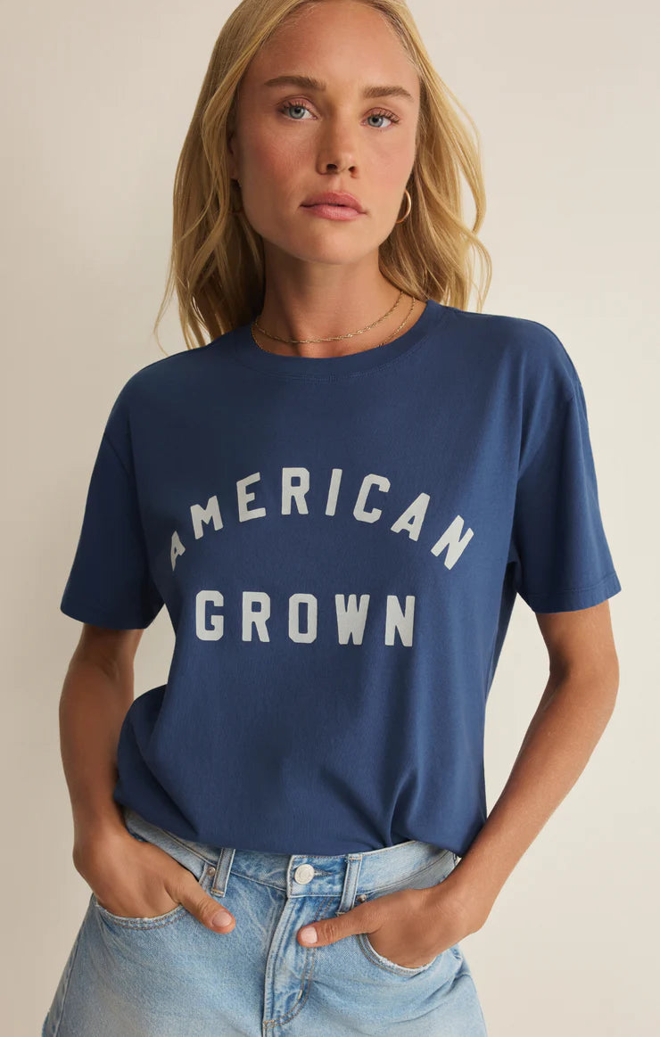 Woman wearing a navy blue t-shirt with 'American Grown' text on a beige background
