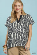 Woman wearing a black and white patterned top against a light blue background
