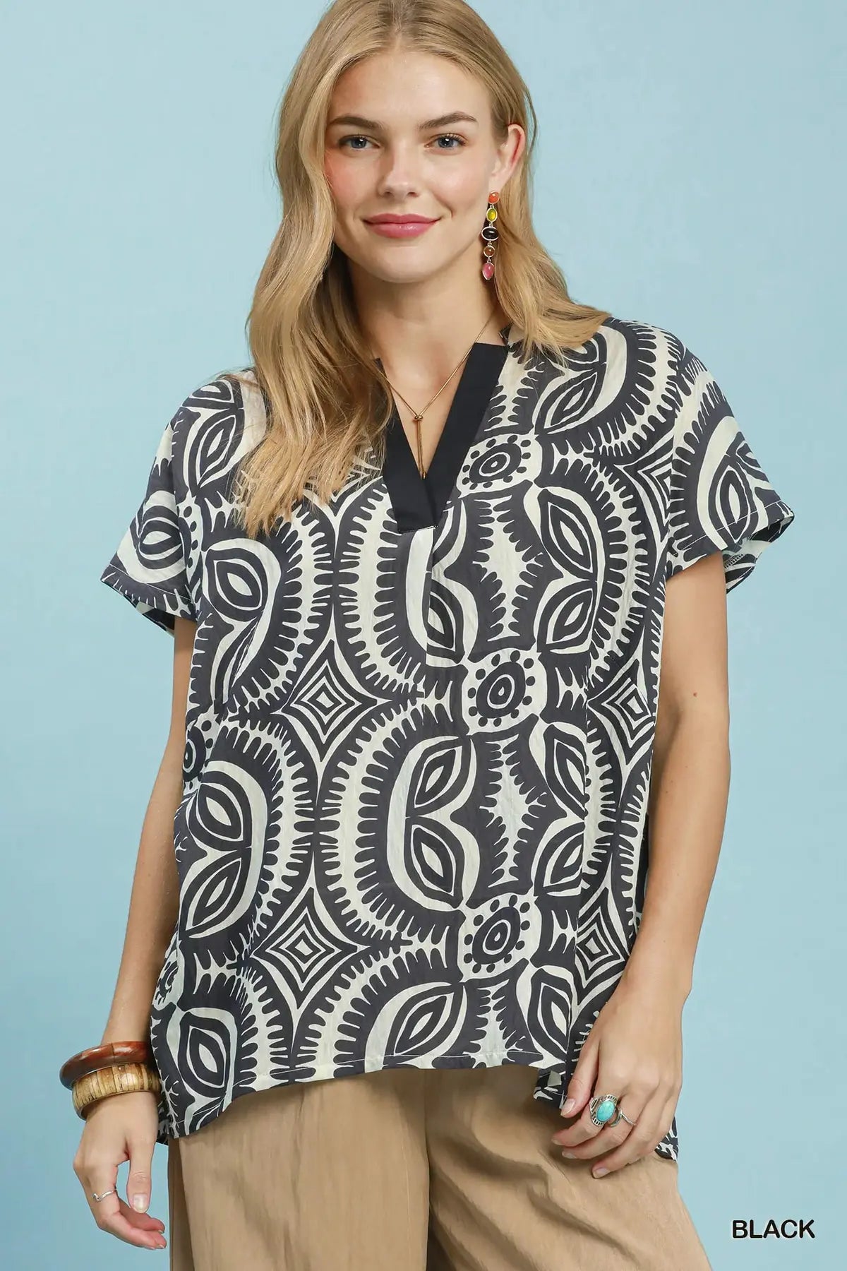 Woman wearing a black and white patterned top against a light blue background