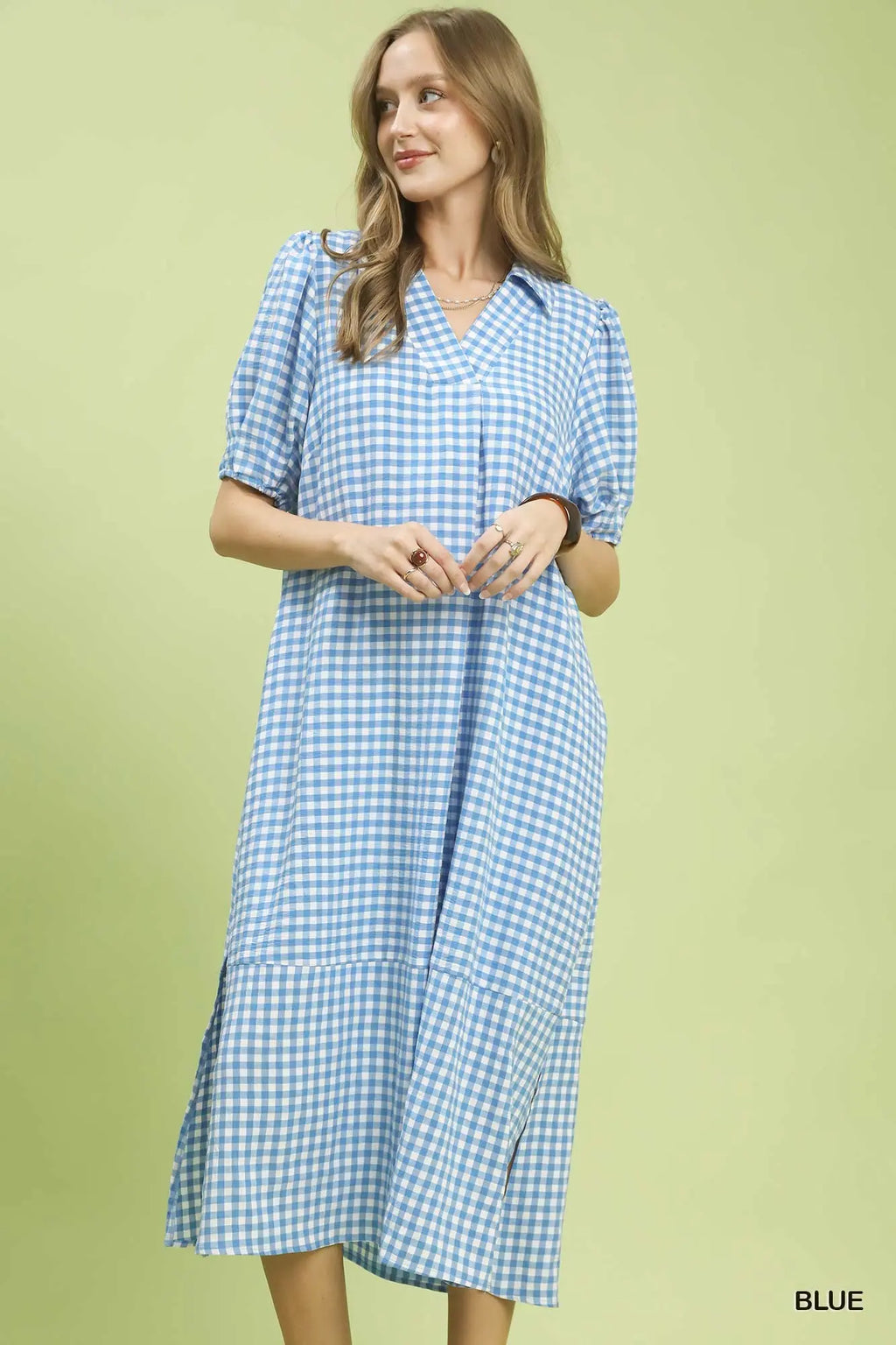Woman wearing a blue checkered dress against a light green background
