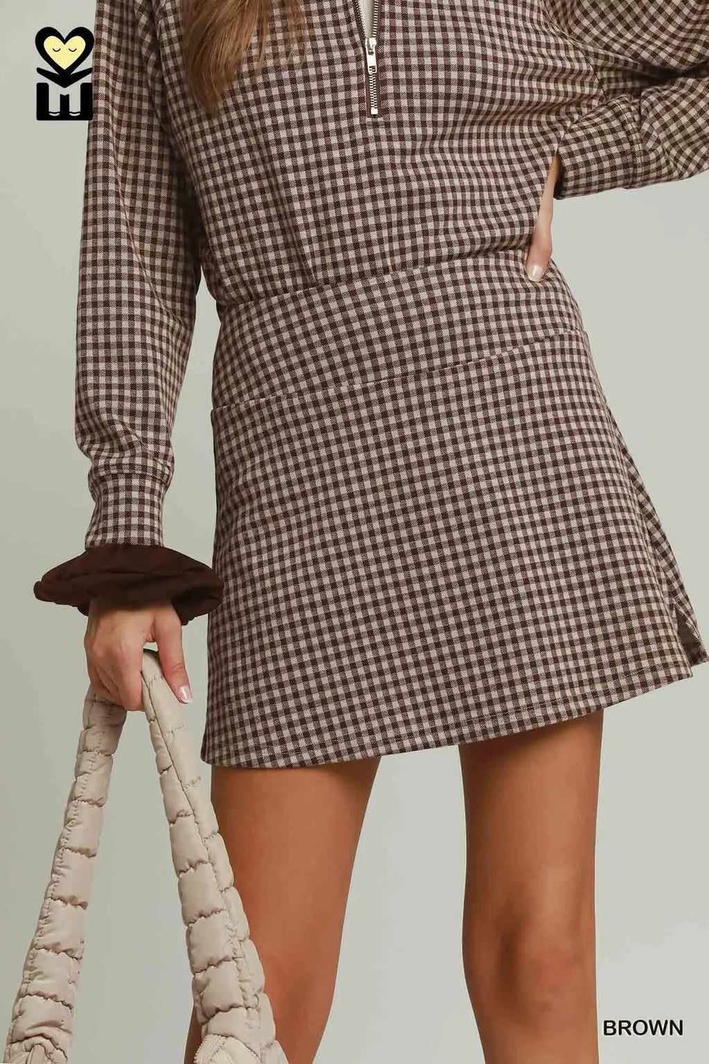 Person wearing a brown and white checkered dress with a plain background