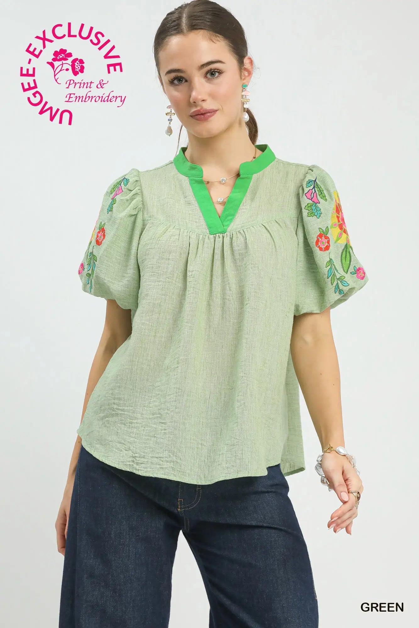 Woman wearing a green blouse with floral embroidery on a white background