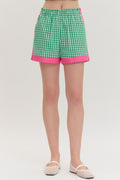 Green and pink checkered shorts worn by a person on a white background