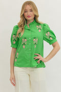 Woman wearing a green blouse with floral embroidery on a white background