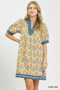 Woman wearing a patterned dress with a honey mix color scheme on a white background