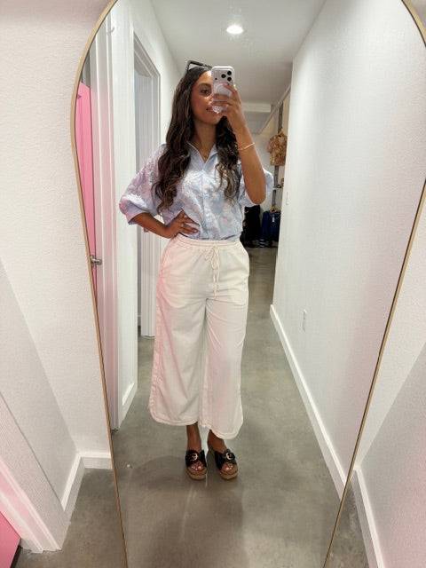 Person wearing a white dress with ruffled sleeves in front of a mirror.