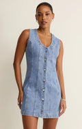Woman wearing a sleeveless denim dress against a plain background